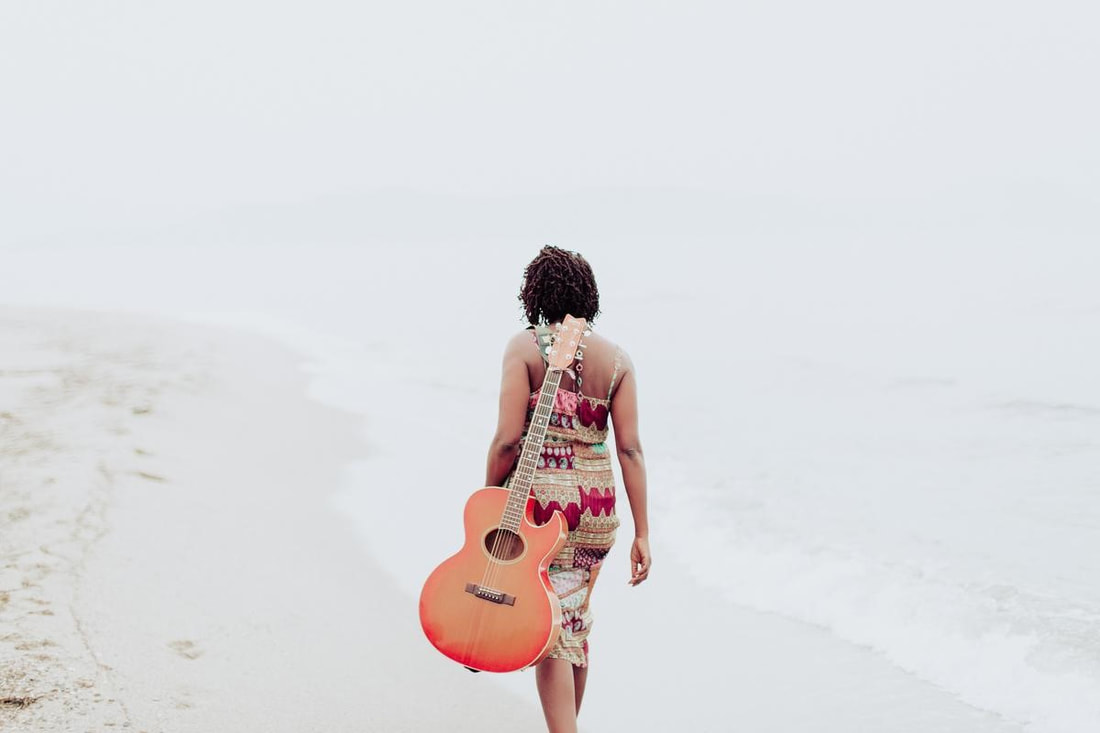 woman with a guitar wallking away