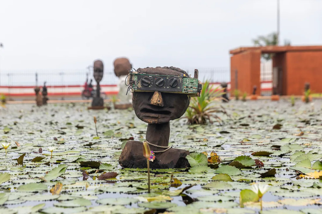 Wooden man in a pond with radio dials for eyes